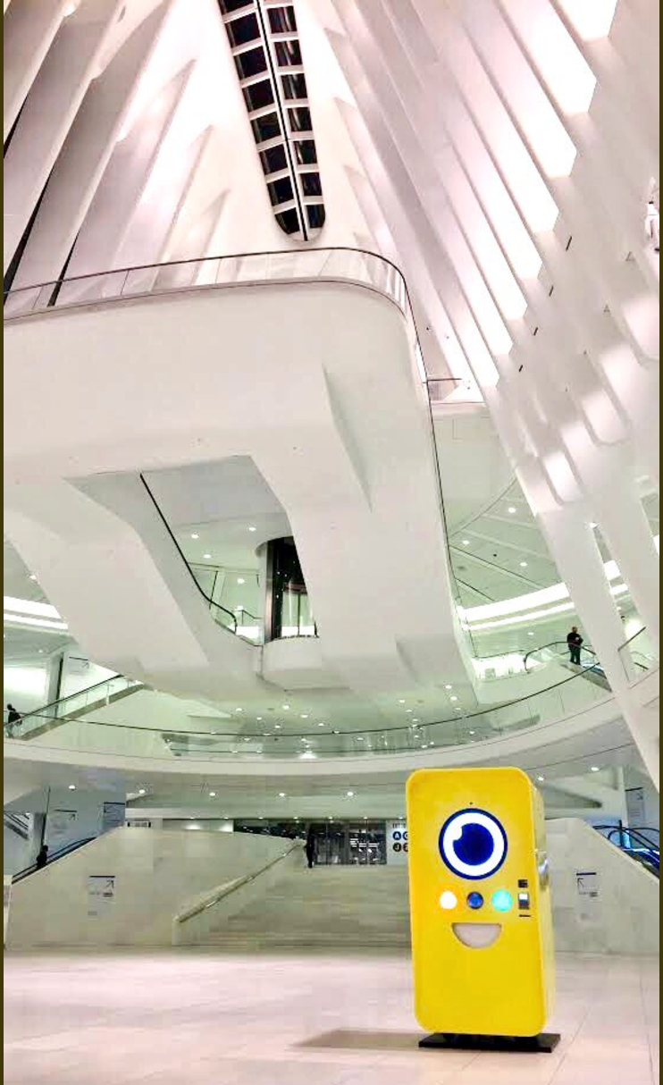 Yellow Snapbot Spectacles vending machine standing in the vast white ribbed atrium of the World Trade Center Oculus