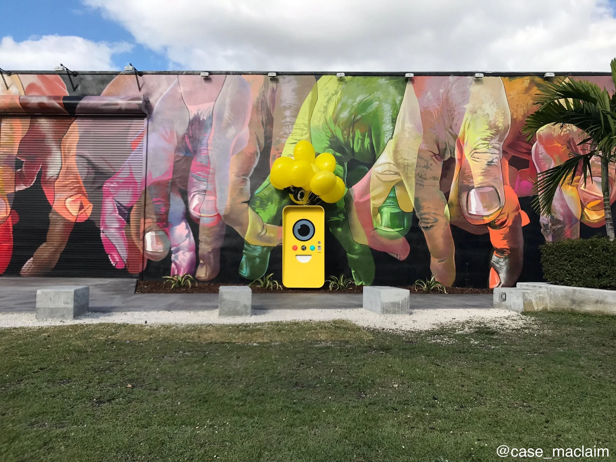 Yellow Snapbot Spectacles vending machine with balloons against a colorful hand mural at Wynwood Walls