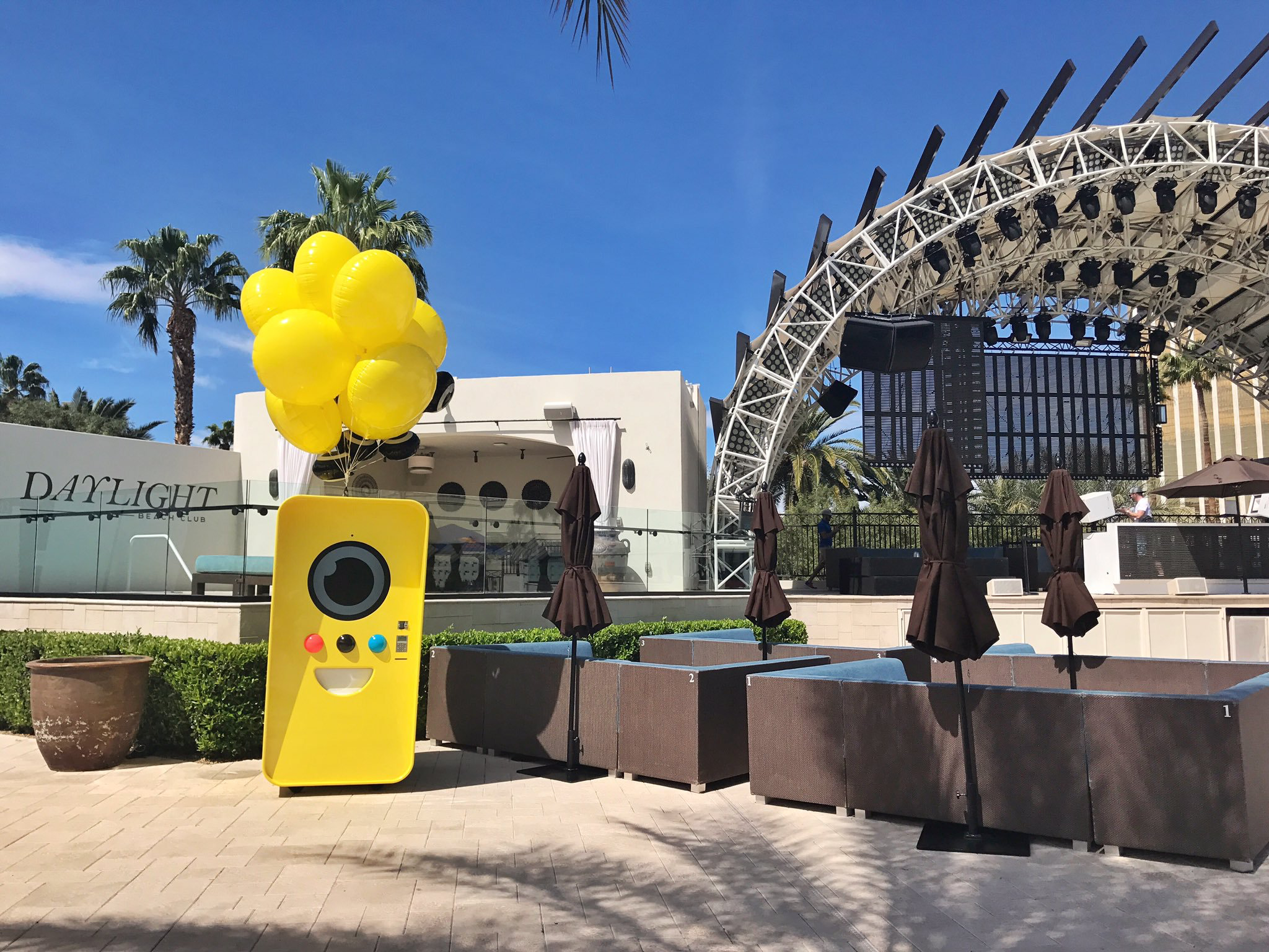 Yellow Snapbot machine with balloons at Daylight Beach Club poolside with cabanas and stage rigging
