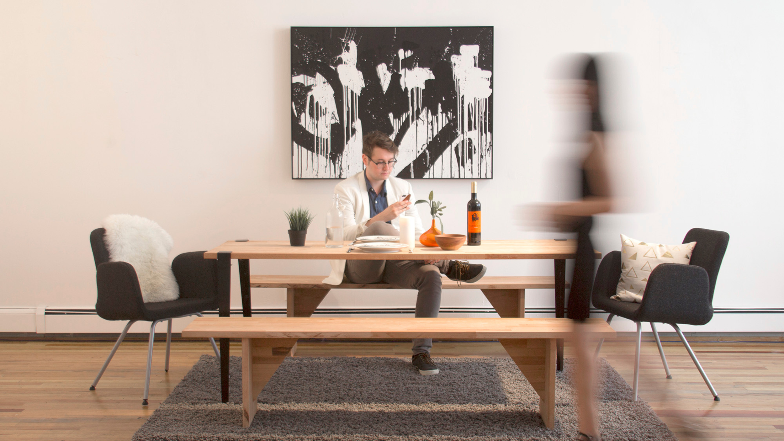 Loft dining room with a wood table; a black-and-white splatter painting on the wall is a Soundwall speaker