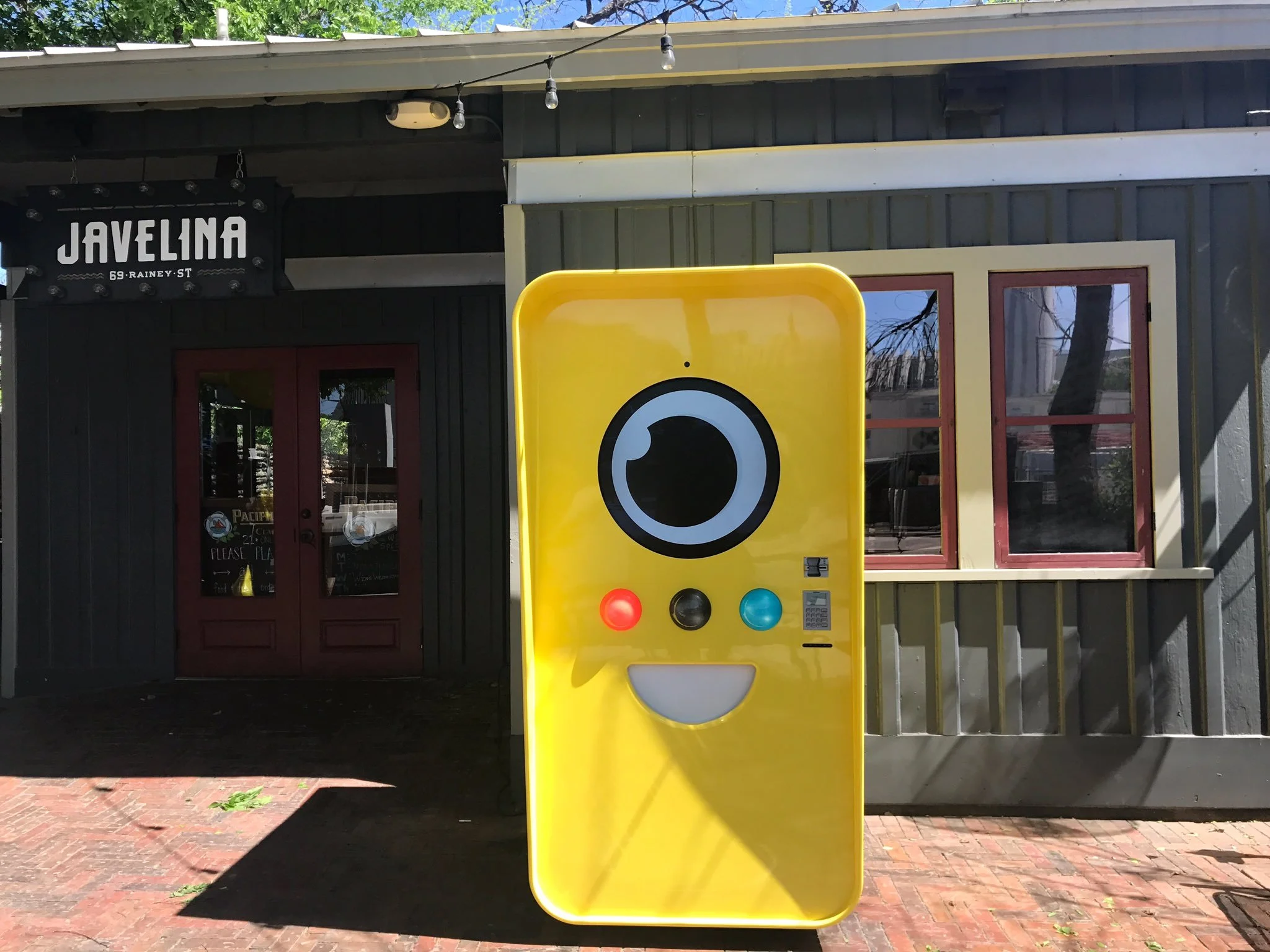 Yellow Snapbot Spectacles vending machine outside Javelina bar, 69 Rainey St, with red and teal buttons