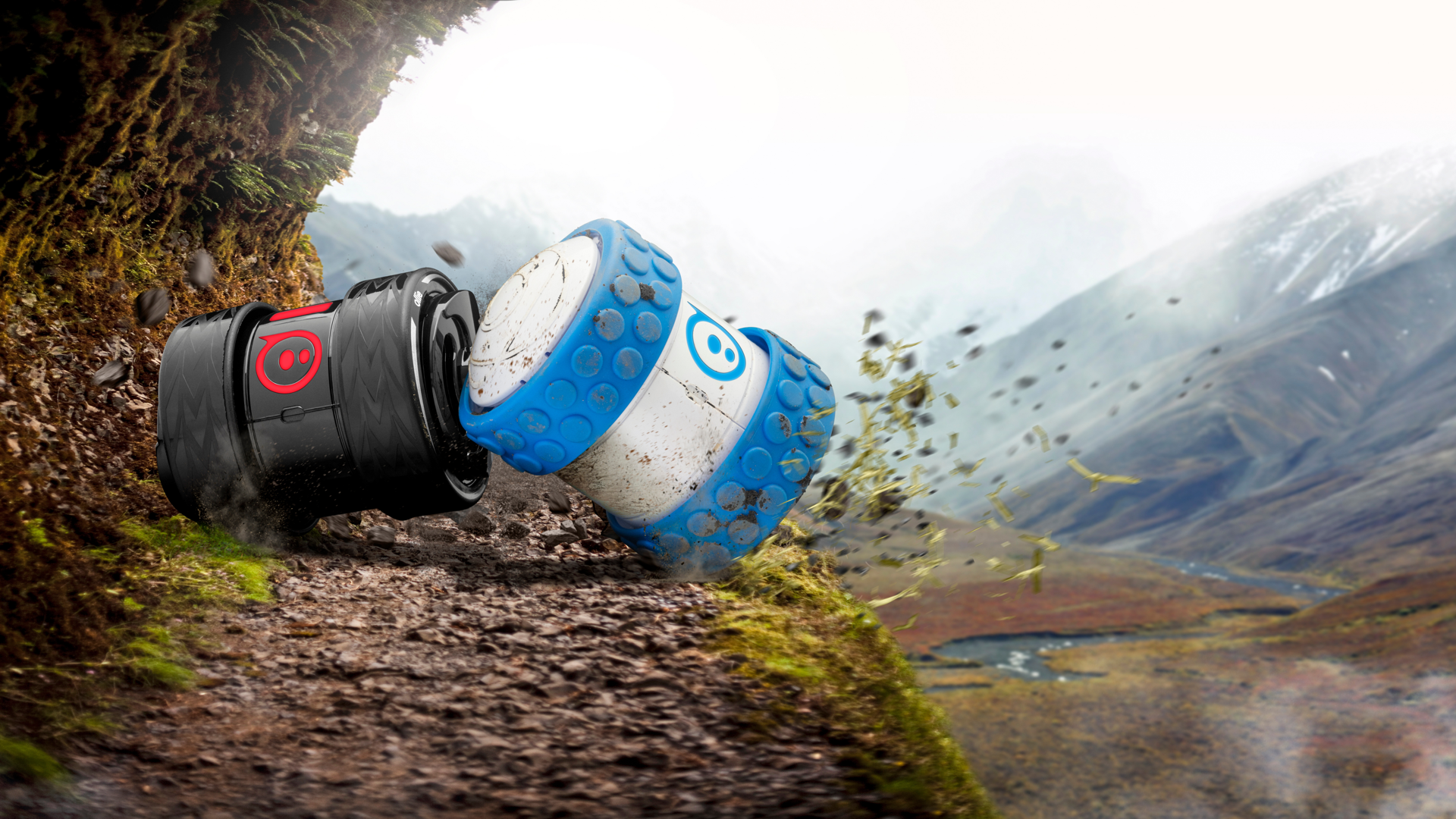Black and blue Sphero Ollie robots racing down a mossy mountain trail, kicking up dirt and grass