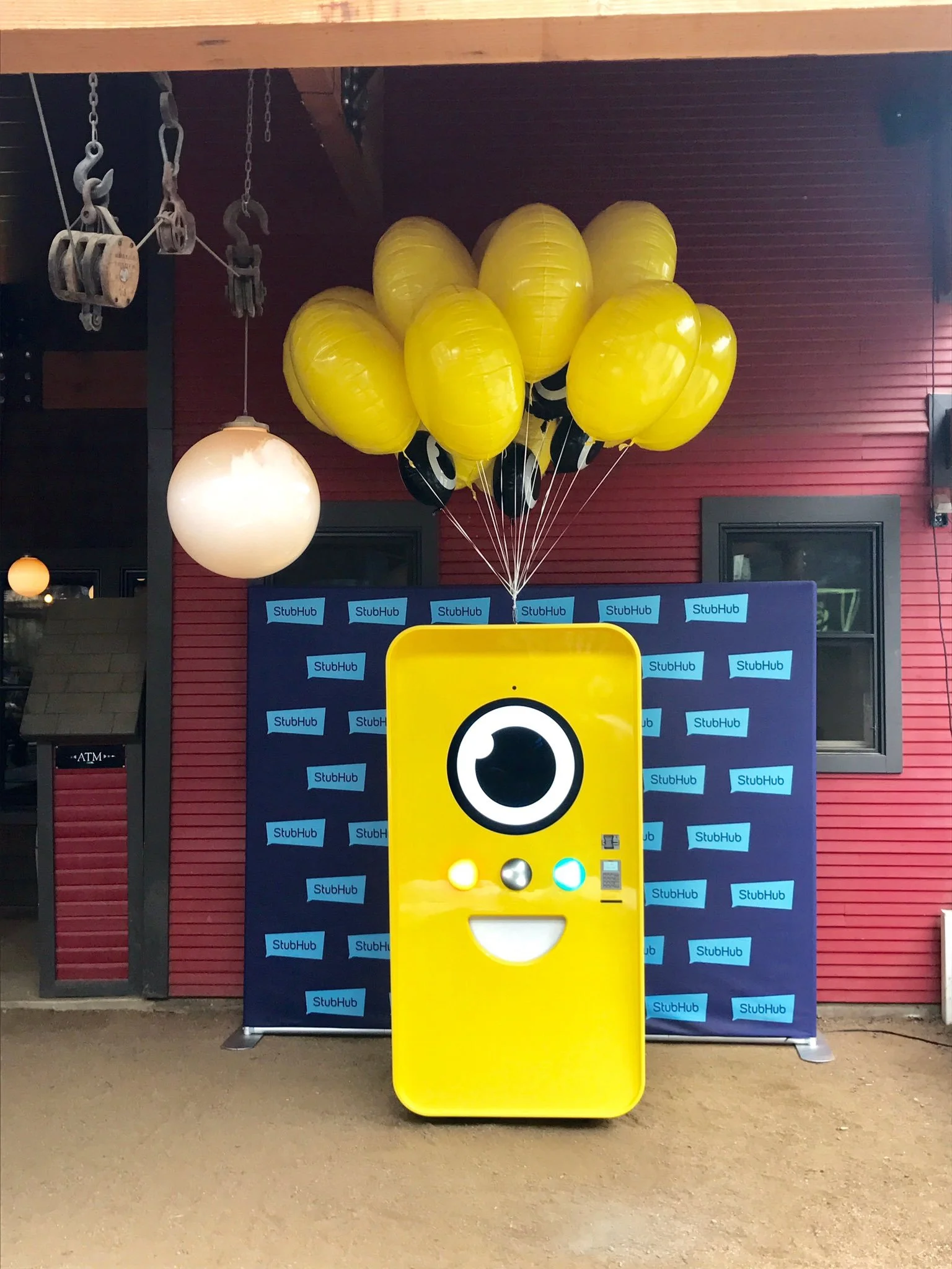 Yellow Snapbot vending machine with a smiling face and balloons in front of a StubHub step-and-repeat backdrop